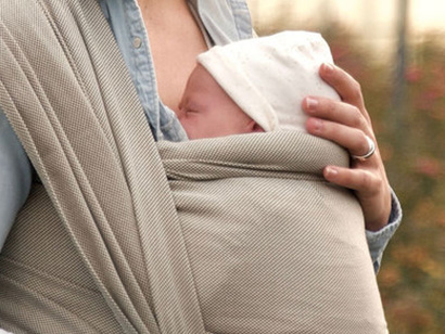 Baby in een geweven draagdoek met nekrol gevoerd van wol voor comfort en ondersteuning van het nekje tijdens slapen in de doek.